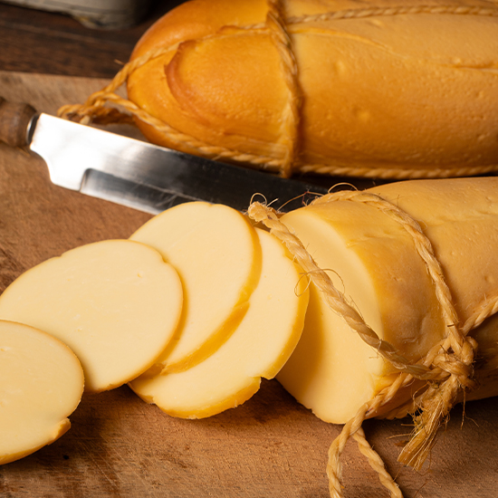Provolone sir u valjku i narezan na okrugle kriške na drvenoj dasci